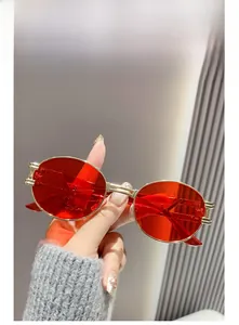 Close-up of retro oval sunglasses with red lenses and golden metallic hollow frames