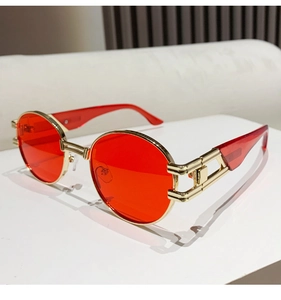 Detailed view of red tinted lenses and golden hollow metal temples of retro sunglasses