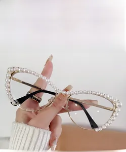Close-up of golden metal cat-eye glasses with pearl embellishments and transparent lenses