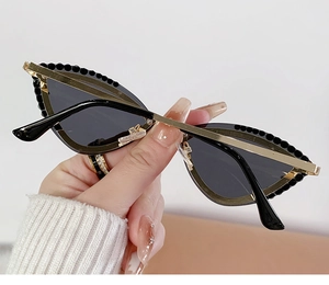 Detail of rhinestone cat-eye sunglasses with gold metal frame and black beaded accents