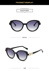 Détail de lunettes de soleil œil-de-chat noires avec chaîne évidée dorée sur les branches