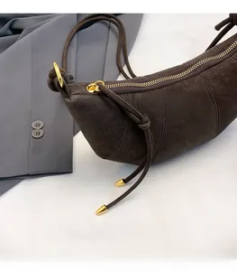 Close-up of smooth gold zipper and suede texture on coffee brown crescent bag