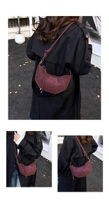 Detail view of burgundy suede croissant bag with vertical stitching and knot shoulder strap