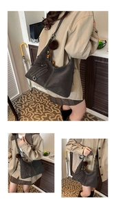 Detail of dark brown tote bag with contrast stitching and decorative bead charm