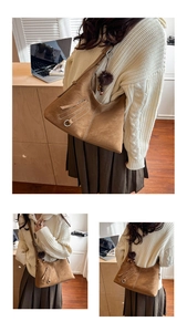 Detail of brown suede tote bag with fringe zipper and decorative plush ball charm