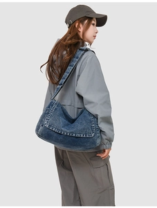 Side view of large denim messenger bag with washed texture and adjustable strap
