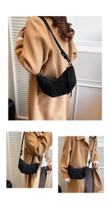 Close-up of black suede croissant shoulder bag with stitched panels and wide strap