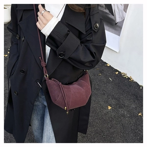 Detail of burgundy faux suede hobo bag with pleated texture and stylish knot strap