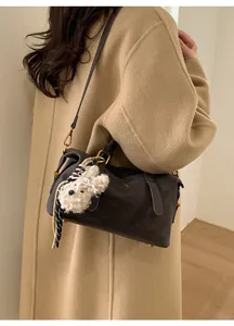 Detail of vintage brown leather Boston bag with gold logo and plush bear charm on model