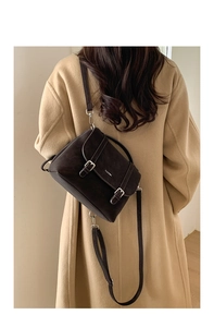 Detail of dark brown vintage tote bag with buckle straps and logo on premium matte leather