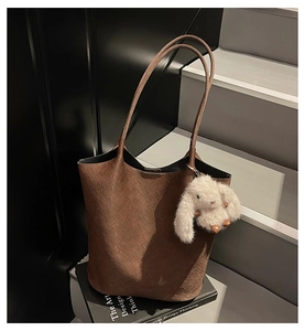 Detail of dark brown woven tote bag featuring a cute white plush bunny charm