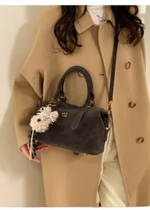 Dark grey Boston bag with plush bear charm styled with a khaki wool coat and beige trousers
