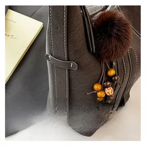 Detailed view of dark brown pebbled leather texture with white contrast stitching and charms