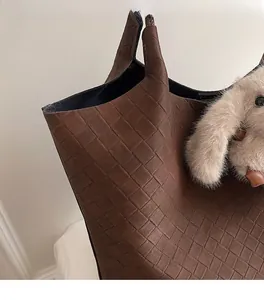 Detail of dark brown woven tote bag texture with cute plush bunny charm on the side