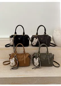 Detail of four retro leather Boston bags with plush rabbit charms and brand lettering