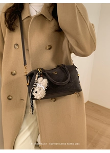 Detail of dark grey suede Boston bag with gold lettering and plush dog charm