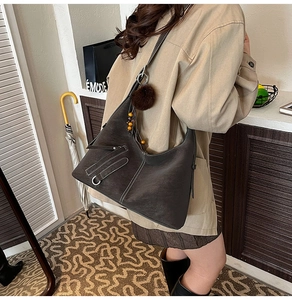 Detail of vintage grey leather tote featuring contrast stitching and plush charm