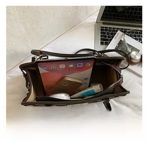 Détail de l'intérieur spacieux du sac en cuir marron foncé contenant tablette et mobile