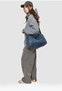 Washed blue denim messenger bag shown on model for a large-capacity casual look
