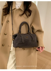Detail of dark gray Boston bag with PAN TOR logo worn with a wool coat in minimalist interior