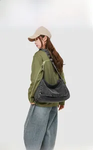 Side view of large washed denim messenger bag in dark grey worn by a model