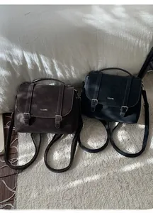Detail of vintage PU leather backpacks in dark coffee and black with metal buckle straps