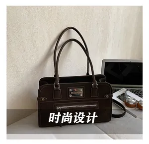 Détail macro du sac fourre-tout rétro marron foncé avec logo métallique et poche zippée