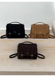 Three retro messenger tote bags in black, camel, and dark brown on stone steps