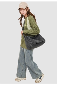 Detail of grey washed denim messenger bag with adjustable strap on female model