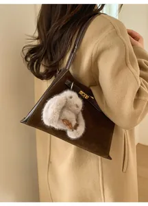Detail of dark brown matte suede bucket bag with gold lock and fluffy rabbit charm