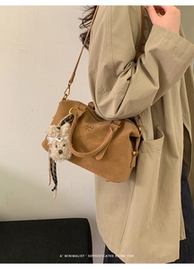Brown vintage Boston bag with plush charm accessory worn by model in trench coat