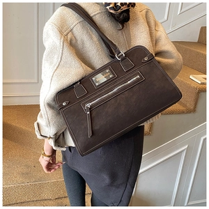 Detail of vintage matte brown tote bag with zipper pocket and metal logo plaque