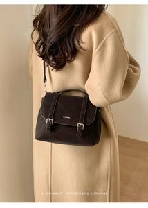 Detail of dark brown vintage faux suede backpack with dual buckle straps for autumn outfits