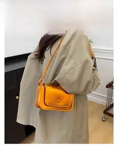 Dettaglio della borsa a tracolla in pelle arancione metallizzato con finitura a specchio lucida