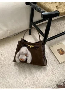 Detailed view of a dark brown suede bucket bag featuring a turn-lock and rabbit charm
