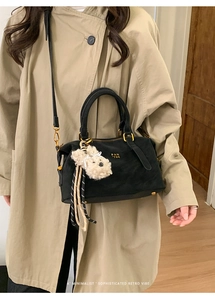 Detail of Boston bag with PAN 'TOR logo and white plush puppy charm on trench coat