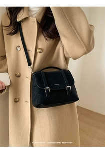 Detail of a vintage black tote bag featuring double buckle straps and silver logo branding