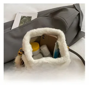 Vue intérieure du sac seau en peluche blanche montrant le rangement pour téléphone et soins