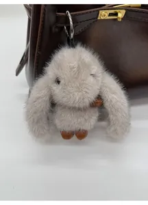 Detail of grey plush bunny charm with long ears on a brown leather handbag accessory
