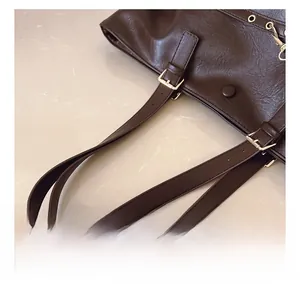 Dettaglio della borsa tote in pelle marrone scuro con fibbia in metallo dorato e rivetti