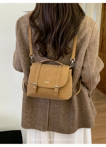 Detail of vintage brown leather backpack worn by model with silver decorative buckle