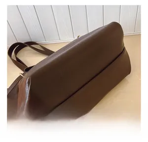 Dettaglio delle cuciture sul fondo e trama della pelle di una borsa tote marrone scuro
