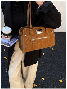 Close-up of vintage brown suede shoulder bag with gold hardware and front zipper detail