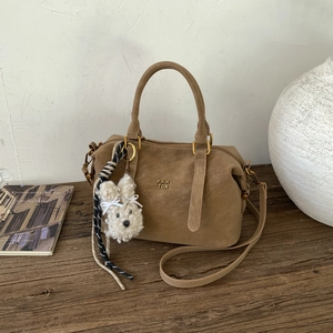 Détail du sac bowling en daim marron avec pendentif chiot en peluche et métal rétro