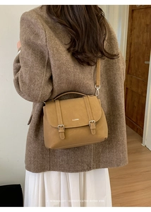 Close-up of retro brown PU leather flap bag featuring dual buckles and CLEAR logo details