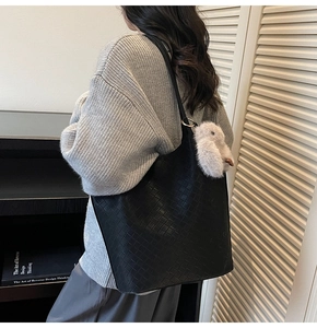 Detail of black woven tote bag texture with cute plush rabbit charm on shoulder strap