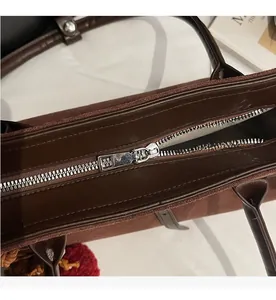 Detail of silver smooth metal zipper on dark brown suede and leather tote bag