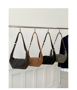 Detail view of four minimalist suede hobo bags in assorted colors with contrast stitching