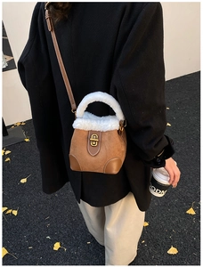 Détail du sac seau en daim marron avec bordure en fausse fourrure blanche et fermoir doré