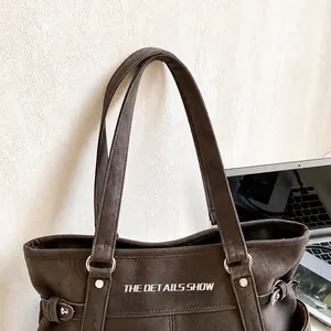 Detalle de las asas reforzadas de un bolso tote con anillo metálico y remaches fijos